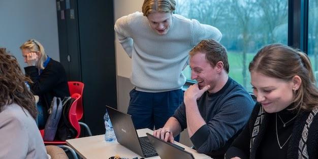 AI trainer geeft een deelnemer persoonlijke begeleiding achter de laptop tijdens een praktische cursus.