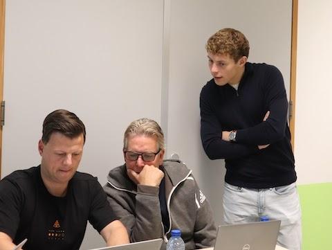 AI trainer geeft een deelnemer persoonlijke begeleiding achter de laptop tijdens een praktische cursus.