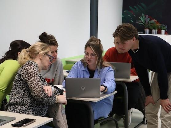 AI trainer geeft een deelnemer persoonlijke begeleiding achter de laptop tijdens een praktische cursus.