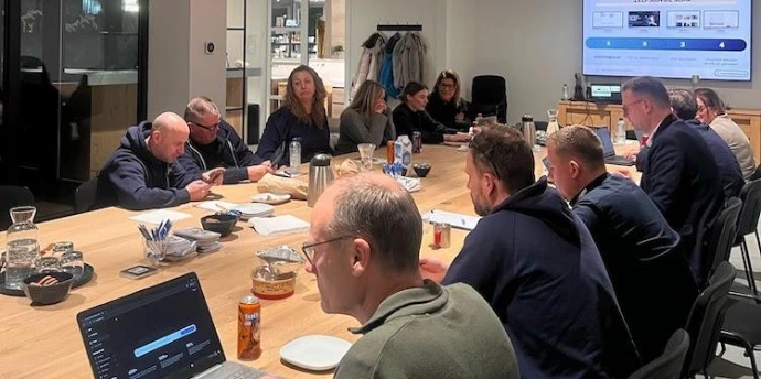 professionals werken geconcentreerd op hun laptops aan AI-opdrachten tijdens een in-company workshop