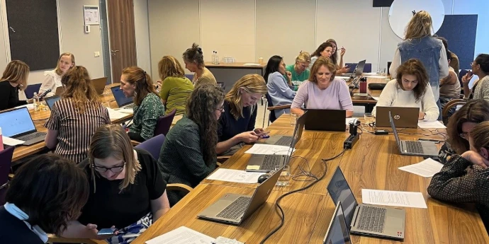 professionals werken geconcentreerd op hun laptops aan AI-opdrachten tijdens een in-company workshop