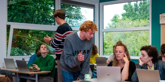 AI trainer geeft een deelnemer persoonlijke begeleiding achter de laptop tijdens een praktische cursus.