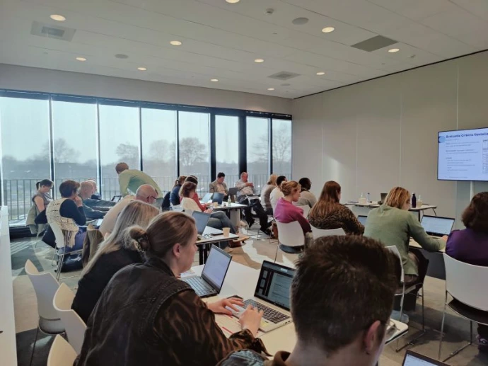 professionals werken geconcentreerd op hun laptops aan AI-opdrachten tijdens een in-company workshop